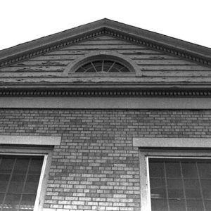 Close-up of brick building with semicircle roof window