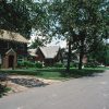 Two-story brick house and single-story brick house on street with trees in yard