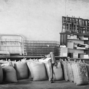 Man laying on large sacks in store with bedroom furniture and stocked shelves with wooden chairs on top