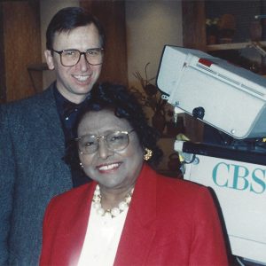 White man and African American woman in front of television equipment