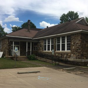 Single-story stone building with covered entrance and parking lot