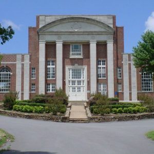 Brick building with stone column facade roundabout stone wall driveway and landscaping