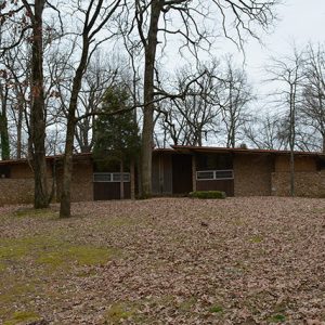 Brick house with angled flat roof on hill covered with fall leaves