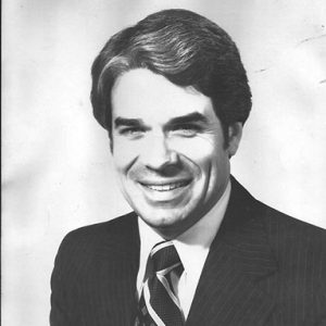 White man smiling in striped suit and tie