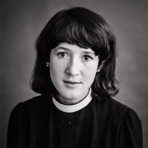 White woman in priest's uniform with white collar