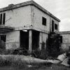 Ruins of two-story concrete building with corner entrance and graffiti