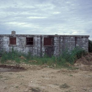 low brick building with bars on its windows on dirt road