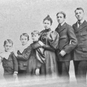 White siblings from toddler to older teen in suits and dresses standing in line