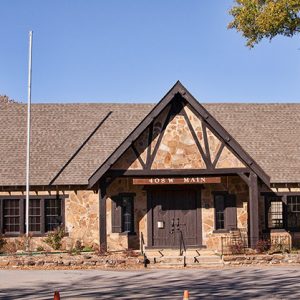 Stone building with flag pole with no flag with sign saying "408 W Main"