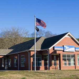 Single-story brick building with sign and flag pole