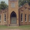 Brick church building with central tower with gothic arch entrance