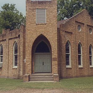 Brick church building with central tower with gothic arch entrance