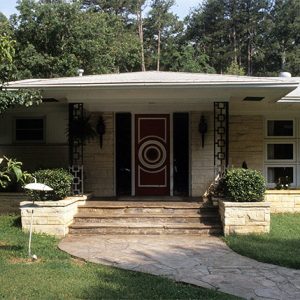 Single-story house with red and white door and covered porch with stone steps and walkway