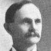 White man with mustache in suit and bow tie