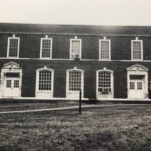 Two-story brick building with framed windows and entrances