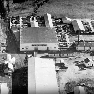 Train tracks next to warehouse buildings outbuildings and parking lot as seen from above