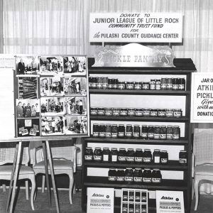 Jars of pickles on wooden shelves next to display stand