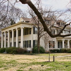 Side view of multistory house with covered porch supported by row of columns