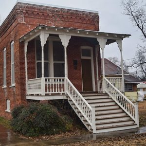 Close-up on brick building with covered porch and stairs