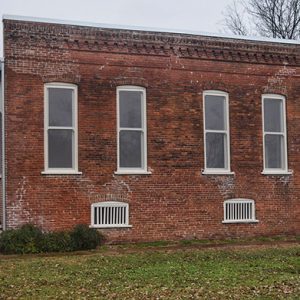 Side vide of brick building with row of windows and covered porch on both ends