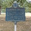 Weathered "Pitman's Ferry" historical marker sign in front of trees