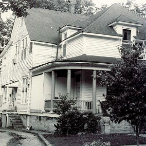 Multistory house with corner porch and trees in neighborhood