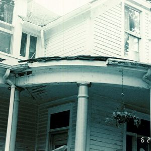 Close-up of multistory house with damaged porch roof