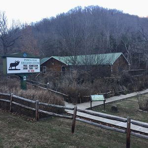 Single-story building with deck wooden fences and sign with Elk logo by walking path