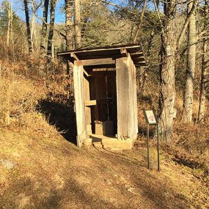 Outhouse with sign in woods