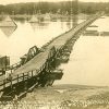 Pontoon bridge with wooden railings on river with boats