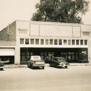 Cars and truck parked outside brick storefronts