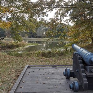 Cannon on wooden platform pointed over body of water