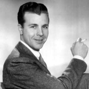 White man in suit and tie holding a cigarette