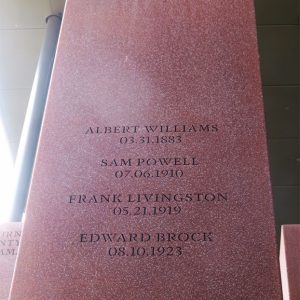 Rust-colored metal rectangle engraved with names and locations