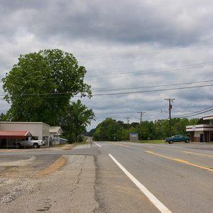 Two-lane road with service station on its right side and garage building on its left side