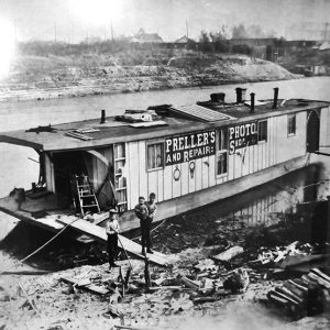 people standing on walking plank outside floating photo studio boat on river