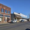 Brick storefronts on street with cars and hanging traffic light