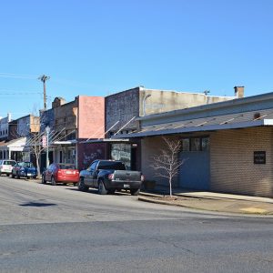 Two-story storefronts on street with water tower in the background