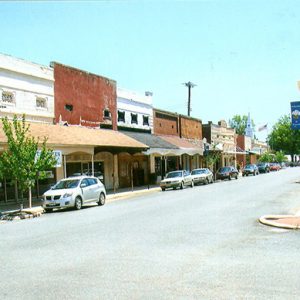 Brick storefronts with awnings on street with parked cars