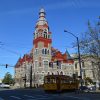 Multistory building with clock tower on city street with yellow trolley car in the foreground