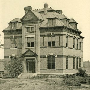 Multistory building with mansard roof and arched windows with bars on them