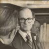 White judge swearing-in white man with glasses in suit