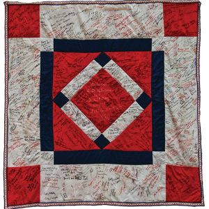 Red white and blue quilt with diamond pattern covered with signatures