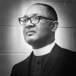 African-American man with glasses in suit with white collar