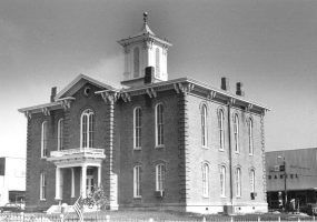 Two-story brick building with arched windows, arched doorway, and bell tower