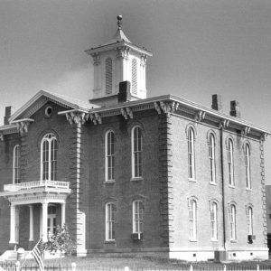 Two-story brick building with arched windows, arched doorway, and bell tower