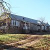 Single-story building with stone walls and covered porches on dirt driveway