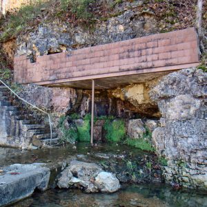 Staircase leading down to open spring under brick and stone roof