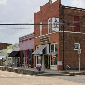 Row of multicolored brick storefronts and multistory Masonic building on street corner