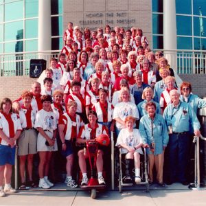 Group of white women in striped uniforms with white men posing on a flight of stairs